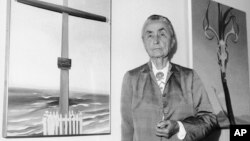 FILE - In this Oct. 8, 1970 file photo, Georgia O'Keeffe stands next to her oil paintings during a press review of 121 paintings, watercolors, and drawings on exhibit at the Whitney Museum of American Art in New York. 