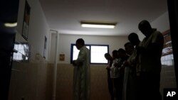 In this photo taken on June 23, 2017, inmates pray with the Imam Mimoun El Hachmi, left, inside the Terni penitentiary. 