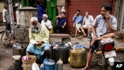 Ethnic Chinese Indians rest behind vendors selling their ware at a roadside market in Kolkata, India, Friday, June 19, 2020. India's prime minister is meeting top opposition leaders Friday as the government tries to lower tensions with China after…