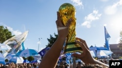 在密苏里州堪萨斯城，阿根廷与瑞士的世界杯四分之一决赛前夕，一名阿根廷球迷在米尔克里克公园的聚会上高举一座世界杯奖杯复制品。(2026年7月10日)