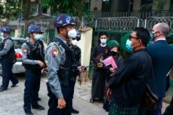 FILE - Myanmar police talk to people gathering for a journalist's hearing, outside the Kamayut court in Yangon, March 12, 2021.