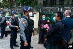 Myanmar police talk to people gathering outside the Kamayut court in Yangon, March 12, 2021.