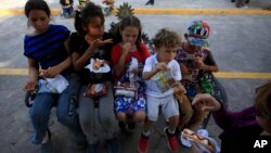 Anak-anak migran menyantap makanan yang disediakan oleh badan amal di Texas, di jembatan internasional Puerta Mexico, Matamoros, negara bagian Tamaulipas, Meksiko, 27 Juni 2019. 