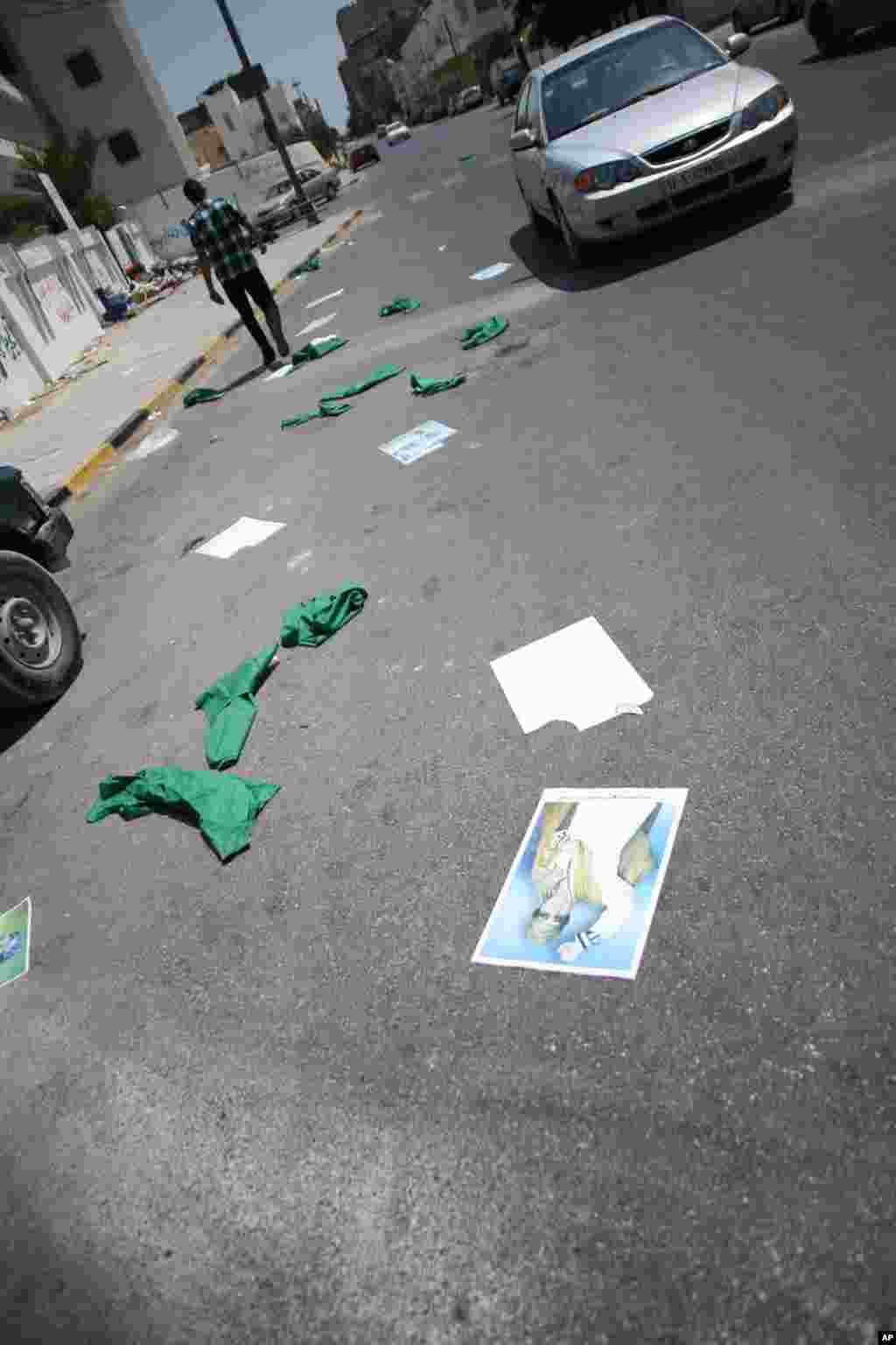 Gadhafi posters and green pieces of clothes -- the color Gadhafi used to represent his government -- are strewn along the street in central Tripoli, August 27, 2011 (VOA - J. Weeks)