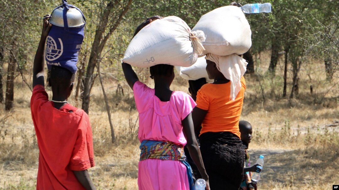 Para perempuan dan anak perempuan berjalan pulang setelah mengambil bahan makanan di Bentiu, sekitar 38 kilometer melalui jalan setapak di semak-semak untuk menghindari penyerangan di jalan utama, dekat Nhialdu, di Sudan Selatan, 7 Desember 2018.