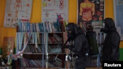 Seorang petugas medis meyemprotkan disinfektan di sebuah sekolah di Palu, Sulawesi Tengah, untuk mencegah penyebaran virus corona baru (COVID-19), 20 Maret 2020. (Foto: Antara via Reuters)