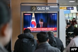 People at a train station in Seoul, South Korea, watch a live television broadcast of South Korea's President Yoon Suk Yeol bowing after the end of his address to the nation, Dec. 7, 2024.