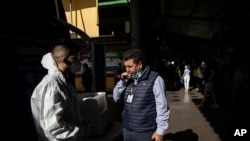 A man blows into a vial for a free COVID-19 rapid test at a bus station for long-distance travelers in Santiago, Chile, Jan. 15, 2021. 
