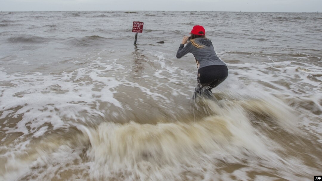 Hannah Jacole Powell-Yost takes photos of a danger sign in the Gulf surf in Gulfport, Miss., as Hurricane Nate approached the Mississippi Gulf Coast, Oct. 7, 2017.