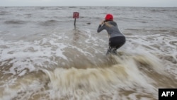 Hannah Jacole Powell-Yost takes photos of a danger sign in the Gulf surf in Gulfport, Miss., as Hurricane Nate approached the Mississippi Gulf Coast, Oct. 7, 2017.