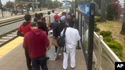 ARCHIVO: Migrantes liberados con citas para presentarse ante una corte de inmigración esperan por un tren en el Aeropuerto Internacional de San Diego, California, EEUU, el 6 de junio de 2024.