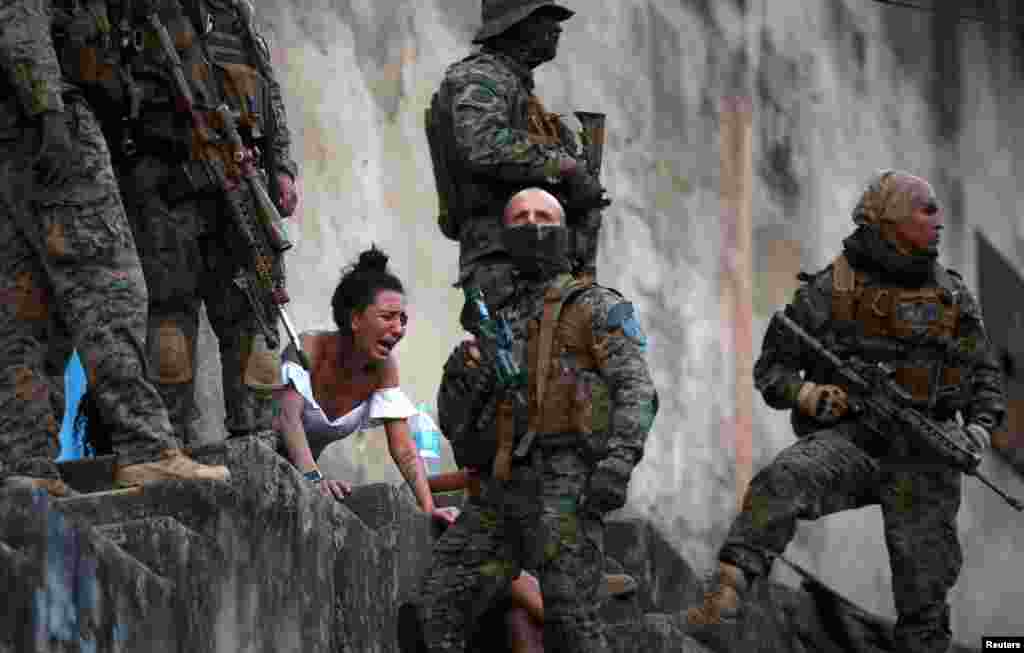 A woman reacts next to the body of a person who was shot near Sao Carlos slums complex during a police operation after heavy confrontations between drug gangs in Rio de Janeiro, Brazil, Aug. 27, 2020.