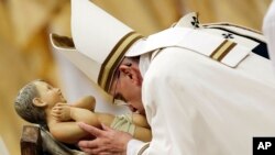 Pope Francis kisses a statue of Baby Jesus as he celebrates the Christmas Eve Mass in St. Peter's Basilica at the Vatican, Wednesday, Dec. 24, 2014.