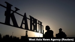 FILE - Taliban soldiers stand in front of a sign at the international airport in Kabul, Afghanistan, Sept. 9, 2021. 