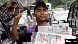 Seorang penjaja koran menawarkan koran dan majalah kepada para pengendara motor di sebuah jalan di Jakarta, 7 Juni 2006. (Foto: Reuters)