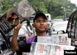 Seorang penjaja koran menawarkan koran dan majalah kepada para pengendara motor di sebuah jalan di Jakarta, 7 Juni 2006. (Foto: Reuters)