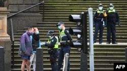 Police check details of residents in the Melbourne central business district in Australia's worst-hit Victoria state, Aug. 9, 2020, as the city struggles to cope with COVID-19 pandemic.