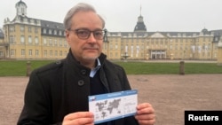 Ketua asosiasi distrik partai AfD,  Marc Bernhard, menunjukkan selebaran kampanye partainya yang mirip tiket deportasi di kota Karlsruhe, Jerman Rabu (15/1). 