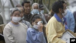 An elder woman wipes her eyes in long lines for food at an evacuation shelter in Koriyama, Fukushima prefecture, Japan, April 2, 2011