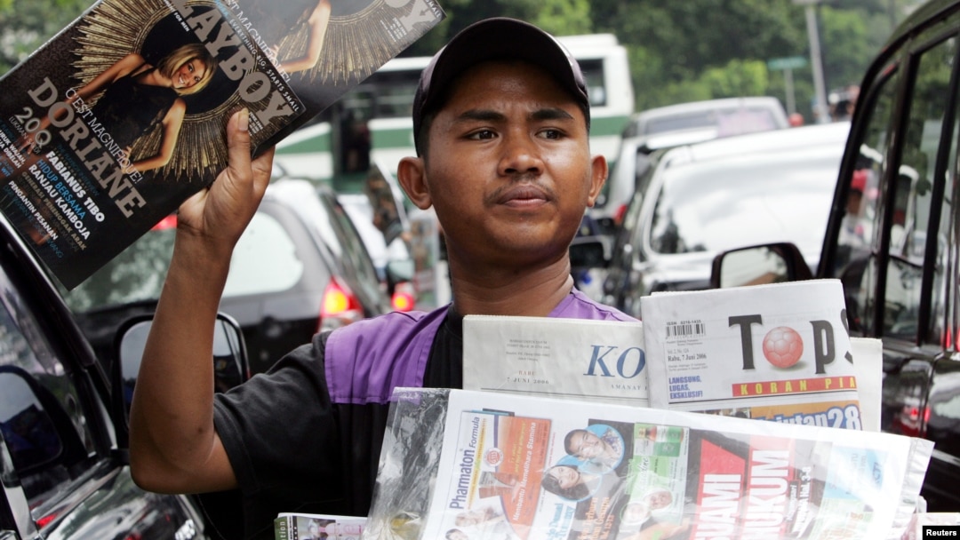 Seorang penjaja koran menawarkan koran dan majalah kepada para pengendara motor di sebuah jalan di Jakarta, 7 Juni 2006. (Foto: Reuters)