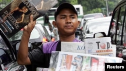 Seorang penjaja koran menawarkan koran dan majalah kepada para pengendara motor di sebuah jalan di Jakarta, 7 Juni 2006. (Foto: Reuters)