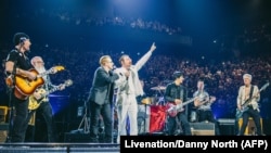 U2 frontman Bono, third from left, and Jesse Hughes, fourth from left, of the Eagles of Death Metal perform with their bands at the packed 16,000-seat AccorHotels Arena in Paris, Dec. 7, 2015.