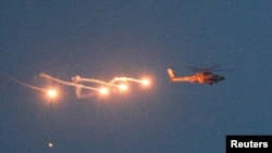 从以色列与黎巴嫩边境的以色列一侧望去，一架以色列直升机飞越黎巴嫩上空时释放了照明弹。(2026年4月16日)