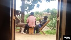 Des combattants FDLR jouent aux cartes avec des civils dans le village de Lusoa, au Nord-Kivu, RDC, 28 mars 2015. (Nicholas Long for VOA News)