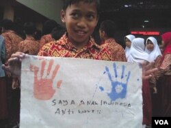 Seorang siswa SD di Bandung memperlihatkan kain integritas hasil karyanya. (VOA/R. Teja Wulan)