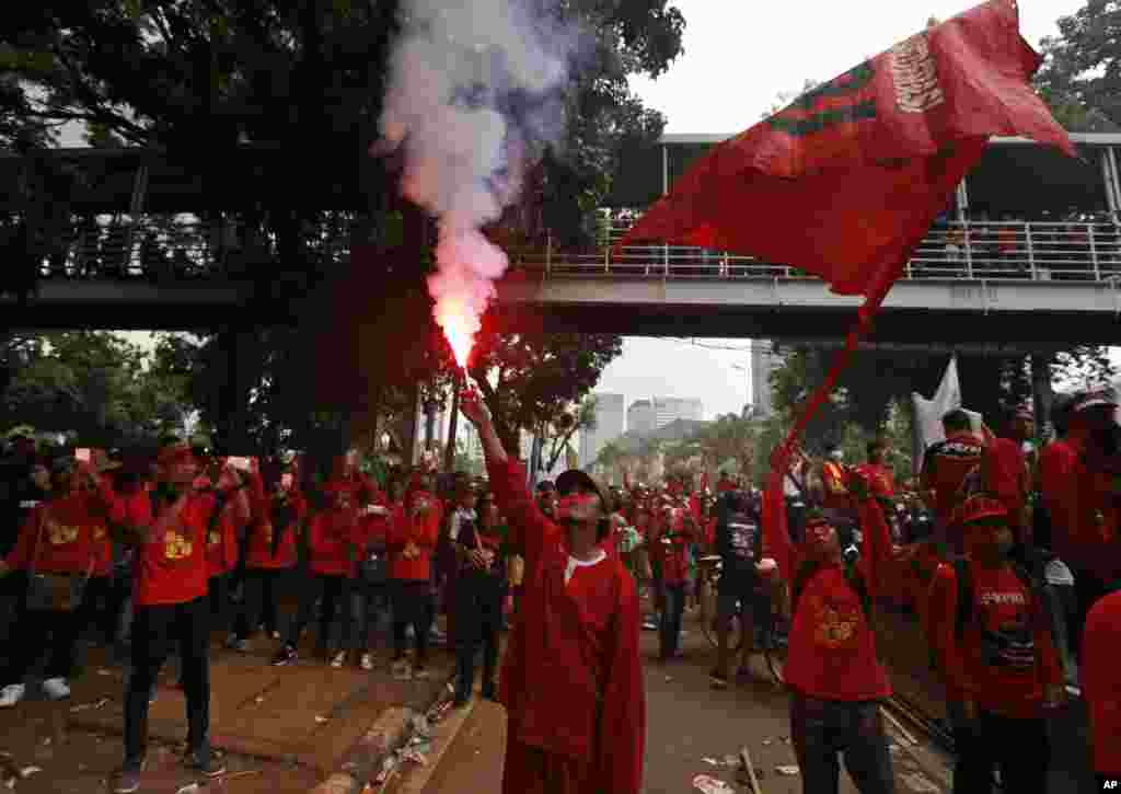 Seorang buruh menyalakan api saat demo Hari Buruh di Jakarta, Senin, 1 Mei 2017.