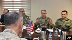 FILE - The U.S. chairman of the Joint Chiefs of Staff, Gen. Joseph Dunford, (back to camera), and Turkey's Chief of Staff Gen. Hulusi Akar (2nd R) talk during a meeting in Incirlik Airbase in Adana, Turkey, Feb. 17, 2017, about the need to fight terror groups in Syria and Iraq.