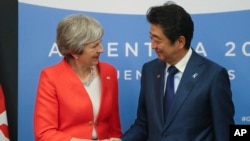 Britain's Prime Minister Theresa May, left, and Japan's Prime Minister Shinzo Abe shake hands prior to a bilateral meeting at the G20 Leader's Summit in Buenos Aires, Dec. 1, 2018. 