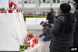 Warga membawa lilin di depan patung Yohanes Paulus II di luar rumah sakit Gemelli tempat Paus Fransiskus dirawat, di Roma pada 24 Februari 2025.