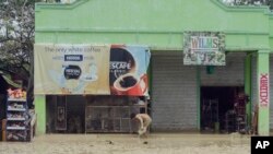 A resident clears the mud off outside his business establishment at Alcantara township, Cebu province in central Philippines Tuesday, Dec. 30, 2014.