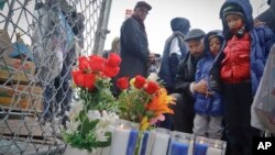 Rev. Kirsten Foy, National Action Network's north east regional director, center, with his sons, Seth, 7, far right, and and Samuel, 5, second from right, pray at a memorial, April 5, 2018, in New York, where Saheed Vassell was shot. 