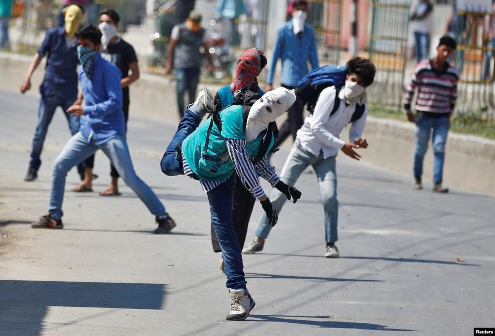Masked Kashmiri protesters throw stones towards Indian security personnel during a demonstration against the plan to resettle Hindus in the valley, according to local media, in Srinagar.