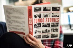 FILE - A journalist reads the "Congo Stories" book by John Prendergast and Fidel Bafilemba with pictures by Ryan Gosling in Washington, D.C., Dec. 14, 2018.