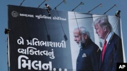 Para pekerja memasang poster raksasa menjelang kunjungan Presiden AS Donald Trump di Ahmedabad, India (20/2). 