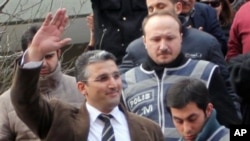 Nedim Sener, a leading investigative reporter of daily newspaper Milliyet, waves after police detained him in Istanbul, Turkey, Thursday, March 3, 2011. Police detained about 10 people, mostly journalists, including Sener, in a crackdown on an alleged sec
