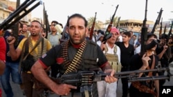 FILE - Iraqi Shi'ite tribal fighters deploy with their weapons while chanting slogans against the al-Qaida-inspired Islamic State of Iraq and the Levant, in Baghdad's Sadr City, Iraq, June 13, 2014.