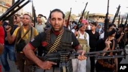 FILE - Iraqi Shi'ite tribal fighters deploy with their weapons while chanting slogans against the al-Qaida-inspired Islamic State of Iraq and the Levant, in Baghdad's Sadr City, Iraq, June 13, 2014.