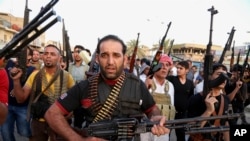 FILE - Iraqi Shi'ite tribal fighters deploy with their weapons while chanting slogans against the al-Qaida-inspired Islamic State of Iraq and the Levant, in Baghdad's Sadr City, Iraq, June 13, 2014.