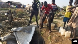 Displaced people draw water from a hole dug in the ground, in the United Nations camp for displaced people in the capital Juba, South Sudan, Jan. 19, 2016.