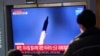 Arhiva - Ljudi gledaju emisiju televizijskih vijesti i snimak lansiranja sjevernokorejske rakete, na željezničkoj stanici u Seulu, Južna Koreja, 14. januara 2022.