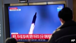 FILE - People watch a TV screen showing a news program reporting about a North Korea missile launch with a file image, at a train station in Seoul, South Korea, Jan. 14, 2022. 
