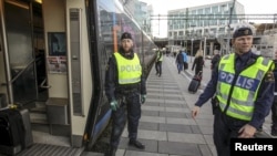 FILE - Police check a train at the Swedish end of the bridge between Sweden and Denmark, in Hyllie district, Malmo, Nov. 12, 2015. Sweden tightened its borders in 2015, and has further restricted its migration policy after the September 2022 election of a new government.