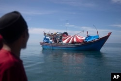 Seorang pria Aceh memeriksa perahu yang membawa Muslim Rohingya yang berlabuh di perairan dekat pantai Labuhan Haji, provinsi Aceh, Rabu, 23 Oktober 2024. (Binsar Bakkara/AP)