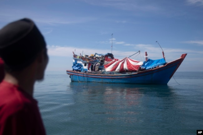 Seorang pria Aceh memeriksa perahu yang membawa Muslim Rohingya yang berlabuh di perairan dekat pantai Labuhan Haji, provinsi Aceh, Rabu, 23 Oktober 2024. (Binsar Bakkara/AP)