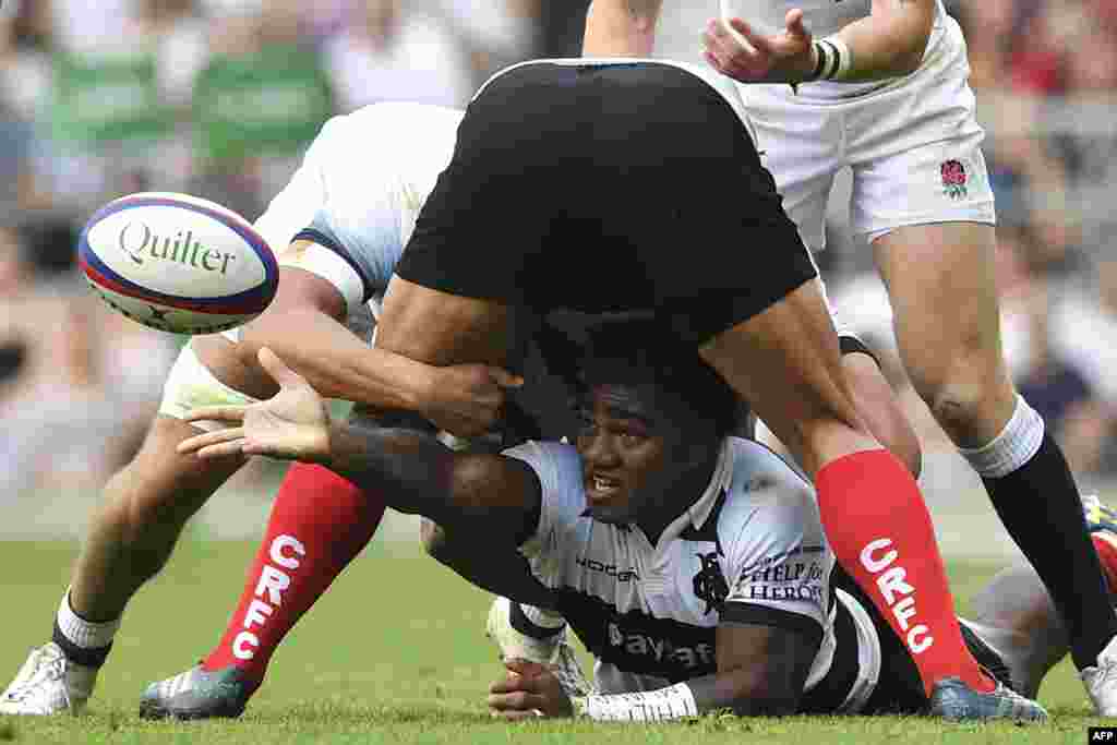 Barbarians&#39; Fijian wing Josua Tuisova (C) passes the ball from the floor during the international friendly rugby union match between England and the Barbarians at the Twickenham, west London.