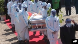 Health officials carry the coffin of Zimbabwean minister Perence Shiri, who died of COVID-19, during his burial in Harare.